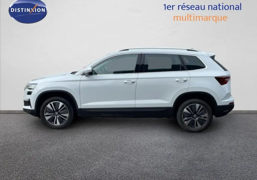 Profil droit d’un Skoda Karoq blanc glacier 2025, SUV compact avec jantes alliage et vitres teintées.