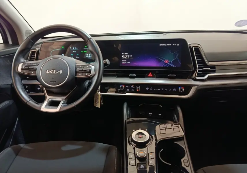 Vue intérieure du tableau de bord et volant du KIA Sportage blanc, avec écran tactile large et commandes modernes.