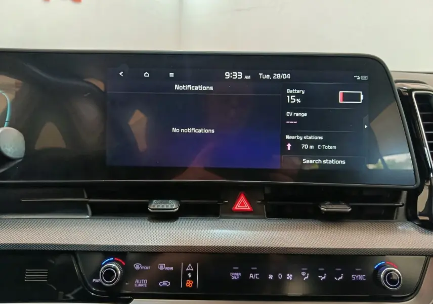 Vue rapprochée du tableau de bord numérique et de la console centrale du Kia Sportage blanc, affichage tactile et commandes climatisation.