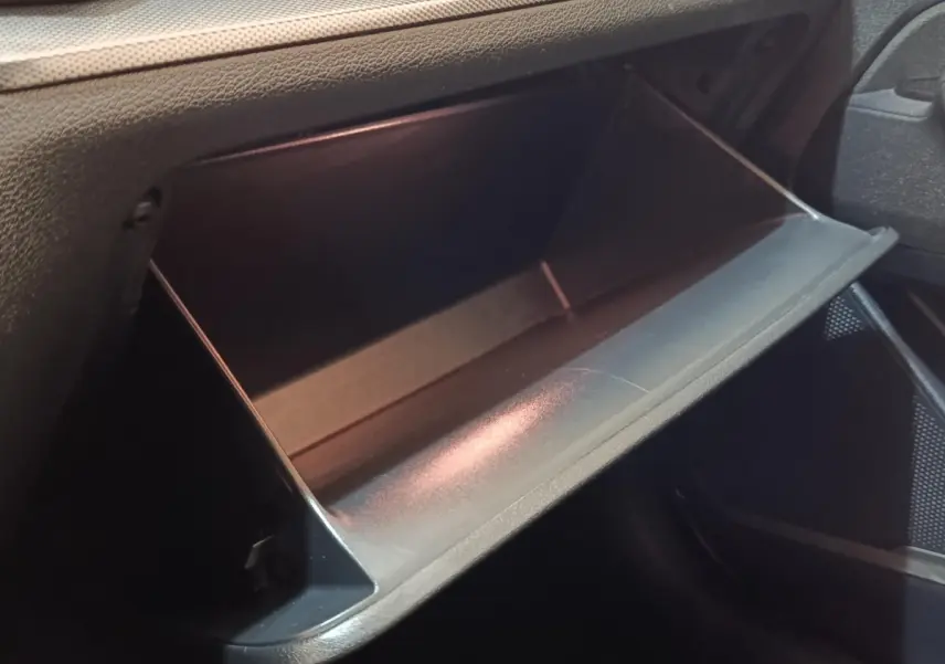 Gros plan sur la boîte à gants ouverte côté passager du Kia Sportage blanc, intérieur noir texturé.
