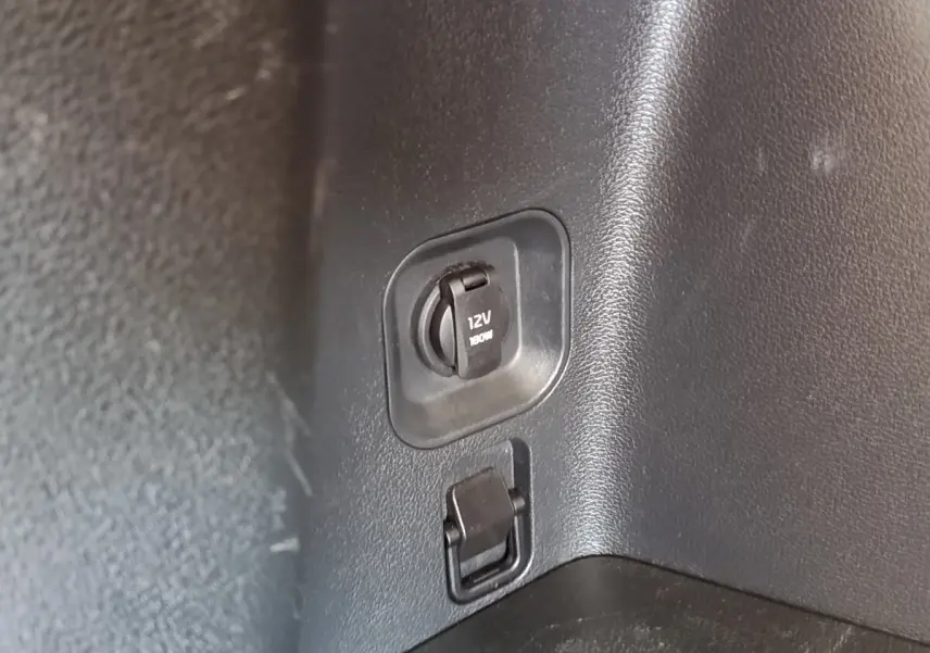 Prise 12V noire dans le coffre du Kia Sportage blanc, version hybride rechargeable 2022.