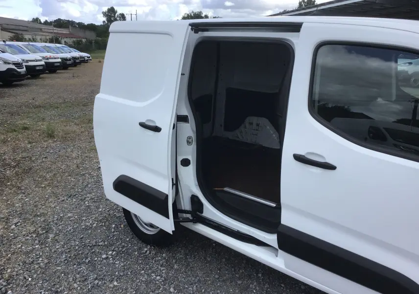 Vue latérale droite d’un Peugeot Partner blanc 2022 avec porte coulissante ouverte montrant l’espace de chargement vide.