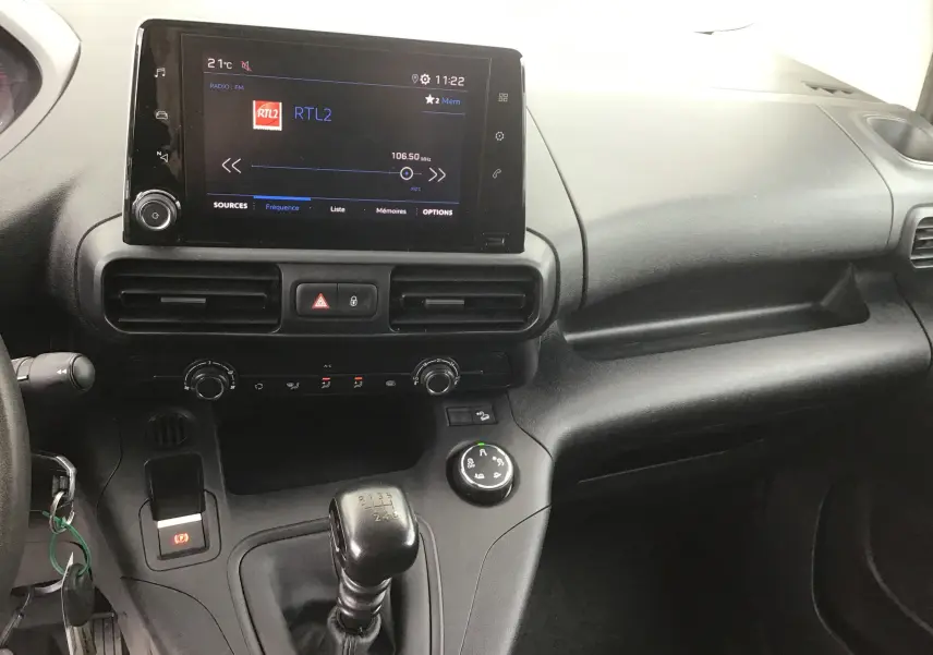 Vue intérieure du tableau de bord du Peugeot Partner blanc 2022, avec écran tactile central et levier de vitesse manuel.
