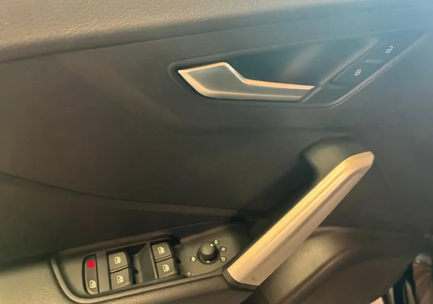 Détail de la porte intérieure côté conducteur d’un Audi Q2 noir, avec commandes des vitres et poignée argentée.
