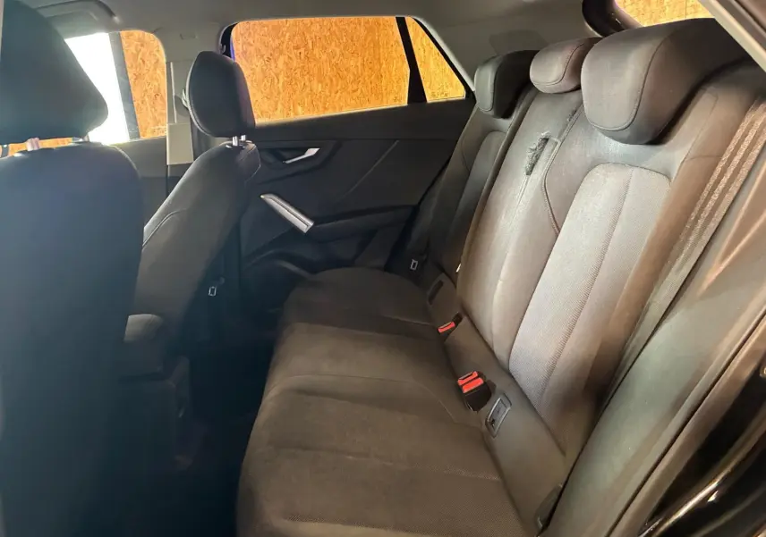 Vue intérieure côté droit des sièges arrière noirs en tissu de l'Audi Q2 30 1.6 TDI 2020 avec ceintures visibles.