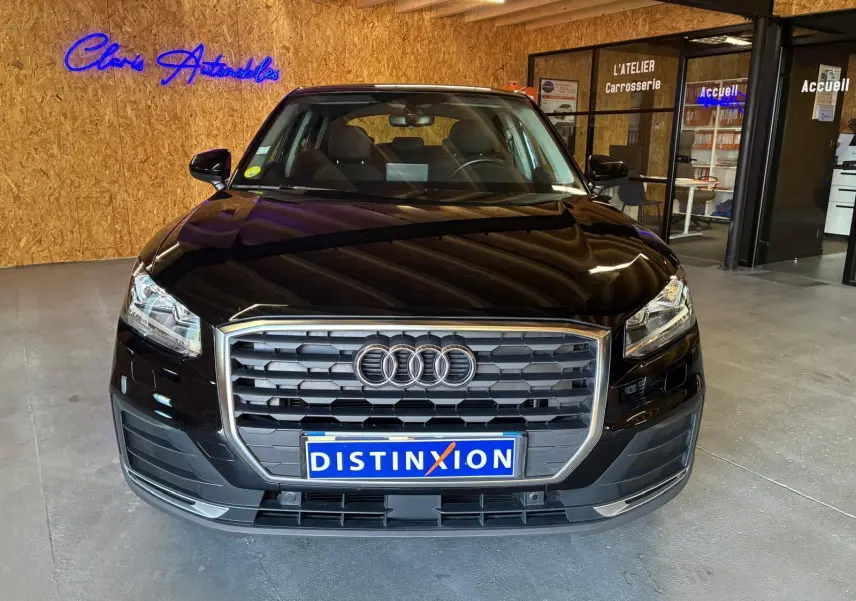 Vue avant d'un Audi Q2 noir 2020 avec calandre hexagonale et logo Audi, en intérieur dans un showroom.