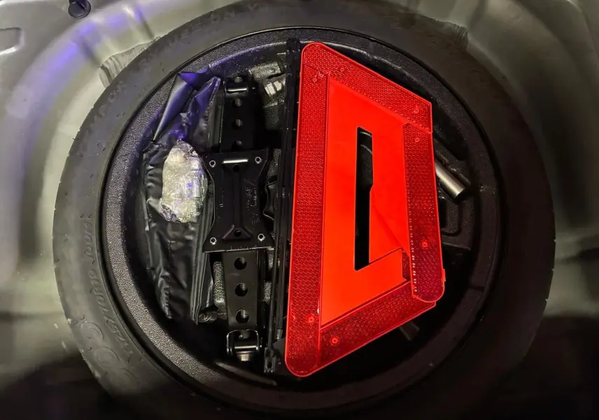Gros plan sur la roue de secours noire d’un Audi Q2 2020 avec triangle de signalisation rouge posé dessus.