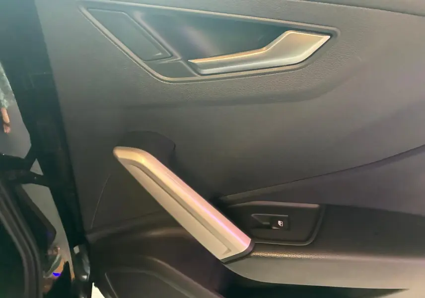 Détail de la porte intérieure côté gauche d’un Audi Q2 noir, avec poignée argentée et bouton de verrouillage.