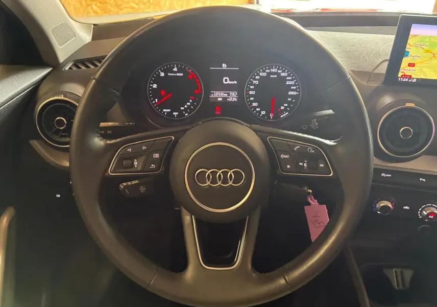 Vue centrée sur le volant noir d'Audi Q2 2020 avec tableau de bord digital et écran GPS visible à droite.