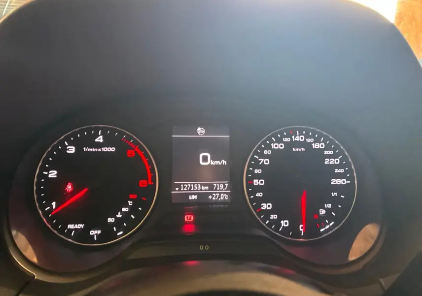 Vue rapprochée du tableau de bord noir d’un Audi Q2 30 1.6 TDI 2020, affichant 0 km/h et 127153 km au compteur.