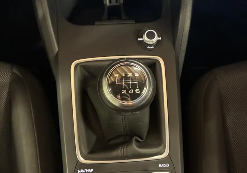 Vue rapprochée de la console centrale noire d’un Audi Q2 2020, mettant en valeur le levier de vitesse manuel et les commandes multimédia.