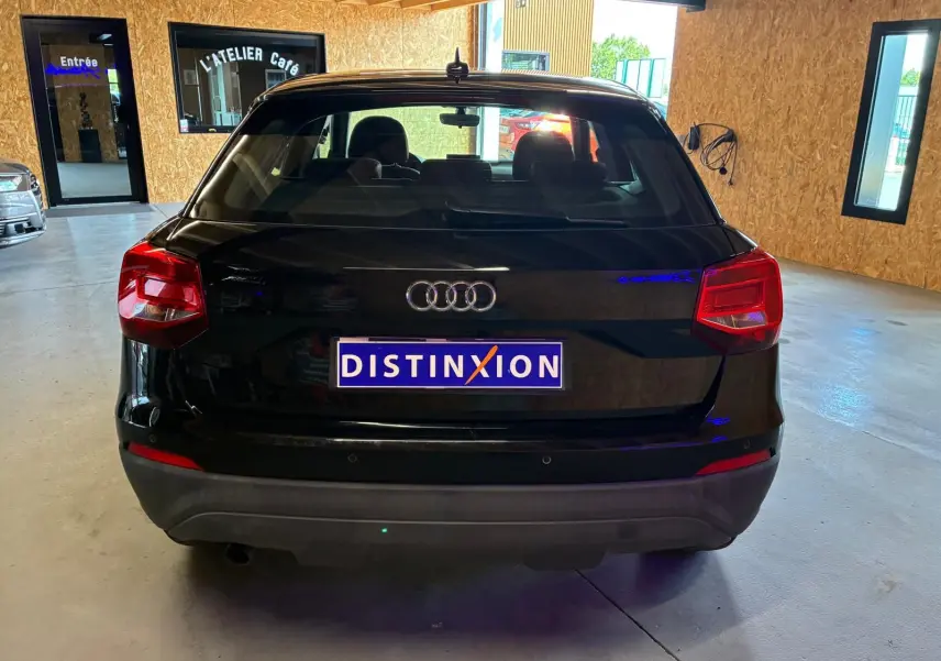 Vue arrière d'un Audi Q2 noir de 2020, stationné en intérieur avec logo Audi et plaque Distinxion visible.