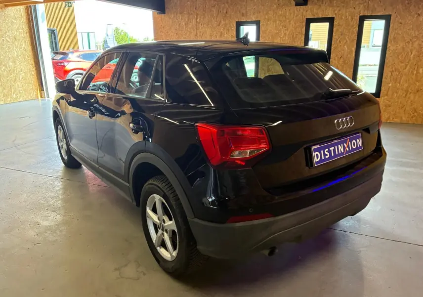 Audi Q2 noir vue 3/4 arrière droit dans un garage, avec feux arrière rouges et jantes argentées.