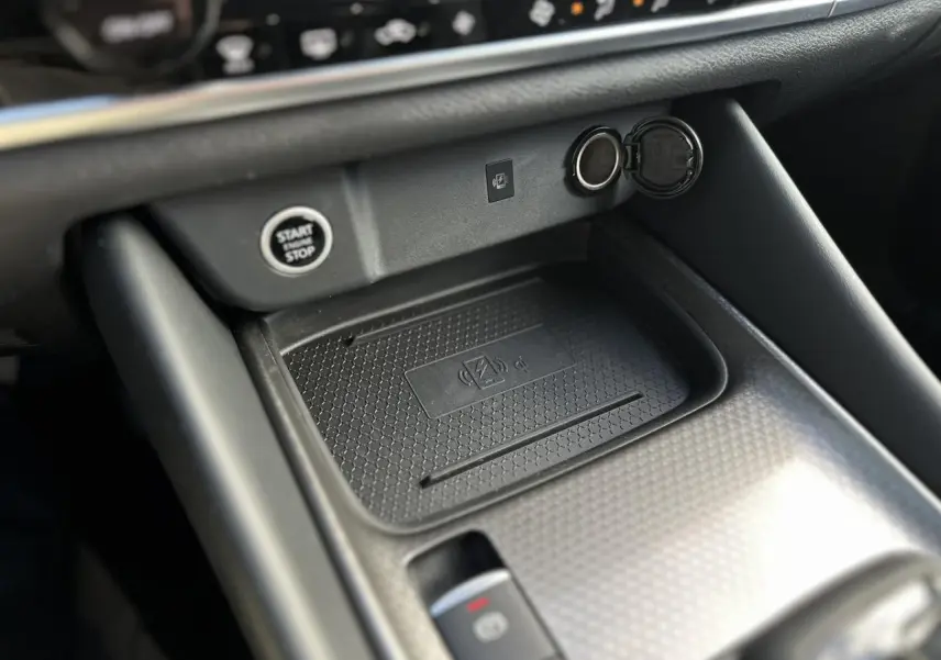 Gros plan sur la console centrale noire du Nissan Qashqai 2025 avec bouton start/stop et chargeur à induction.