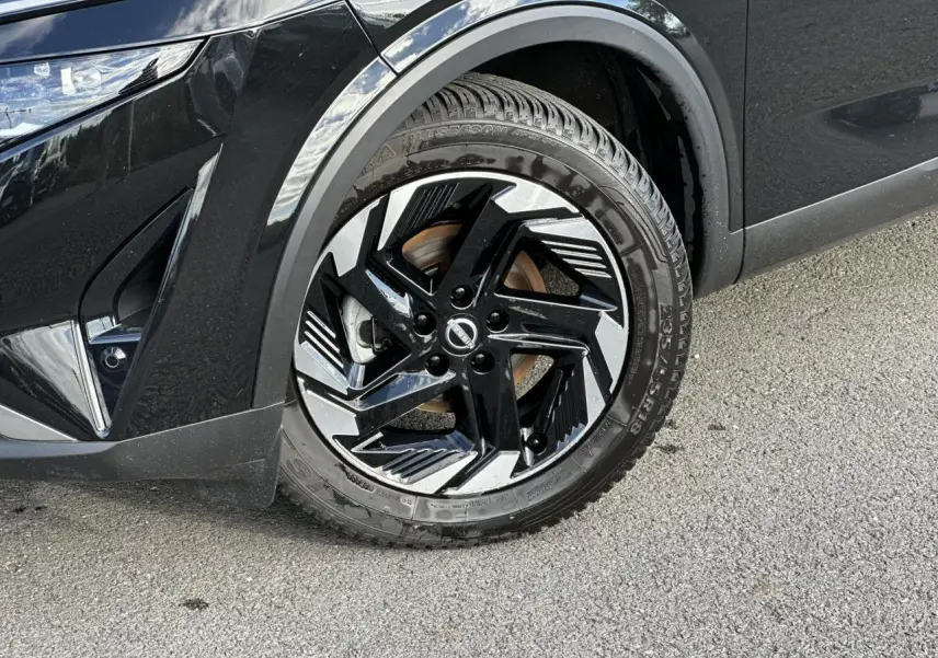 Gros plan sur la roue avant gauche noire nacrée du Nissan Qashqai 2025 avec jante alliage bicolore et détails modernes.