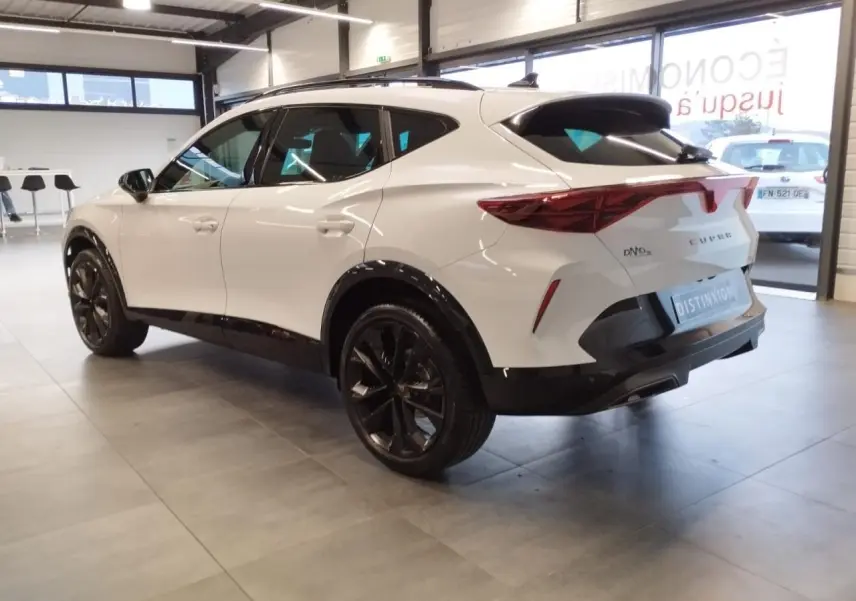 Vue 3/4 arrière droite d’un CUPRA Formentor blanc Nevada avec jantes noires et bandeau lumineux arrière Tri-LED.