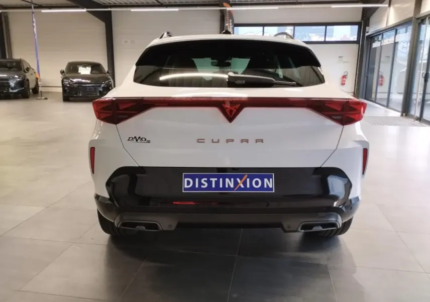 Vue arrière d'un CUPRA Formentor blanc Nevada avec feux arrière en bandeau lumineux et double sortie d'échappement noire.