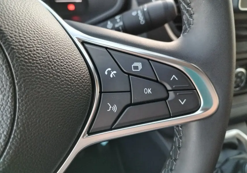 Gros plan sur les commandes multifonctions noires et argentées du volant en cuir du Nissan Primastar blanc 2025.