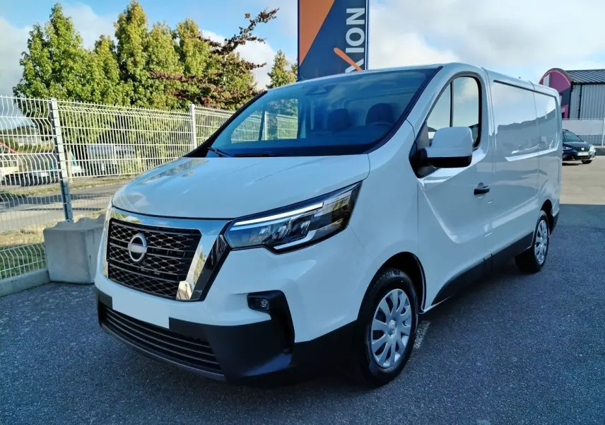 Nissan Primastar blanc en 3/4 avant droit, fourgon utilitaire avec calandre chromée et phares LED modernes.