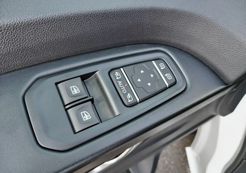 Gros plan sur les commandes de lève-vitres et réglage des rétroviseurs côté conducteur du Nissan Primastar blanc 2025.