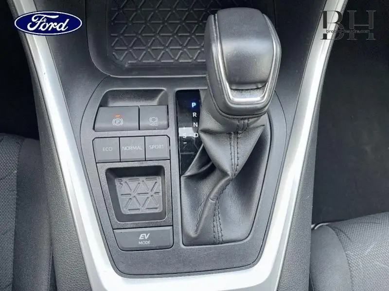 Gros plan sur la console centrale noire du Toyota RAV4 2022, mettant en valeur le levier de vitesses automatique et les boutons de modes de conduite.