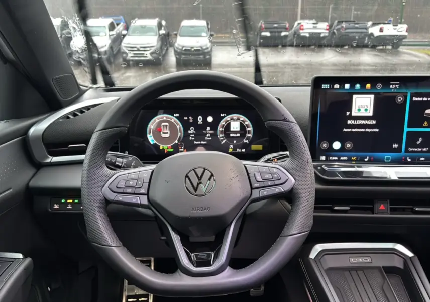 Vue frontale du tableau de bord et volant cuir multifonctions du Volkswagen T-Roc blanc toit noir, avec écran digital et commandes tactiles.