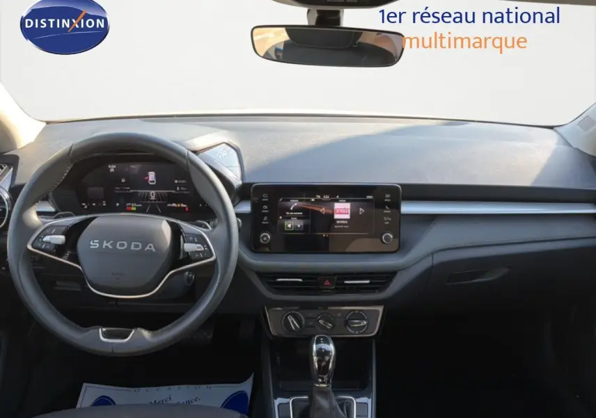 Vue intérieure avant du tableau de bord gris graphite d'une Skoda Fabia 2025 avec volant multifonction et écran tactile central.