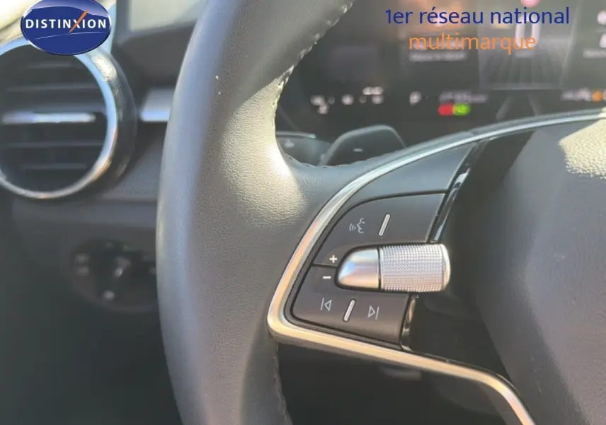 Gros plan sur les commandes au volant cuir de la Skoda Fabia 2025, avec détails métalliques et tableau de bord flou.