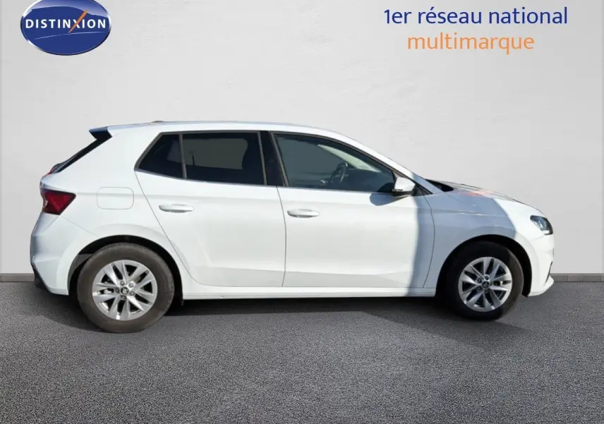 Vue de profil côté gauche d'une Skoda Fabia blanche garée sur sol gris, avec jantes alliage et vitres teintées.