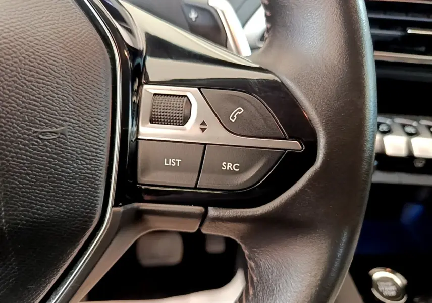 Gros plan sur les commandes gauche du volant cuir noir du Peugeot 3008 2022, avec bouton appel et molette de réglage.