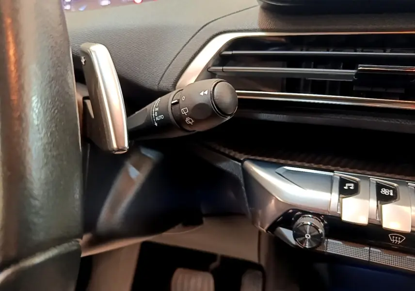 Détail intérieur du volant et commande d’essuie-glace du Peugeot 3008 bleu, avec tableau de bord et aérateurs visibles.