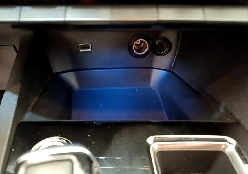 Vue rapprochée de la console centrale noire du Peugeot 3008 2022 avec prise USB et allume-cigare ouverte.