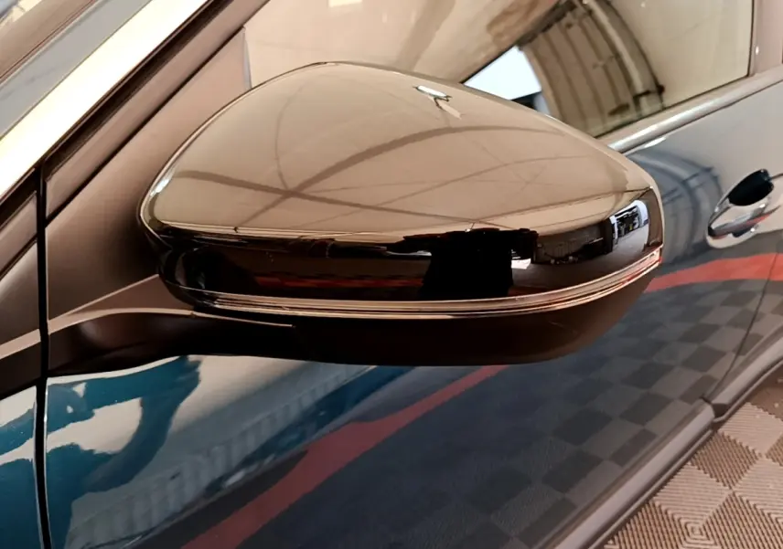 Rétroviseur droit noir brillant sur Peugeot 3008 bleu, vue rapprochée côté conducteur avec reflet intérieur.