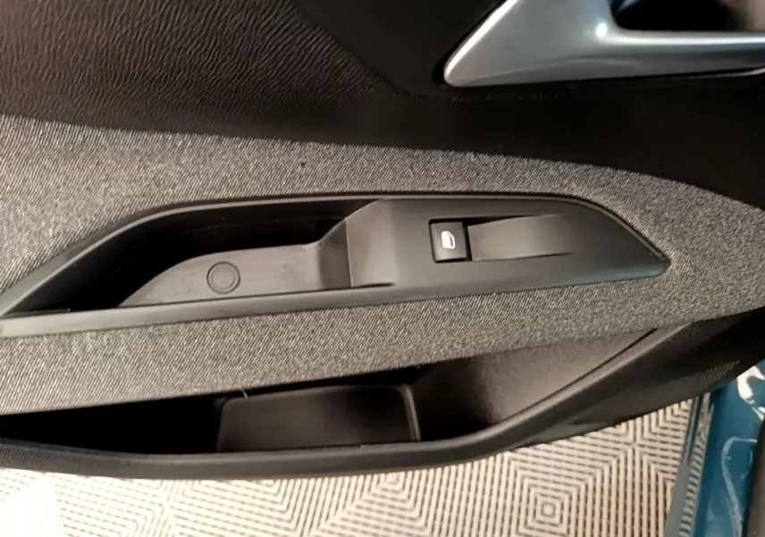Détail de la commande de lève-vitre côté conducteur sur porte intérieure tissu noir du Peugeot 3008 bleu 2022.