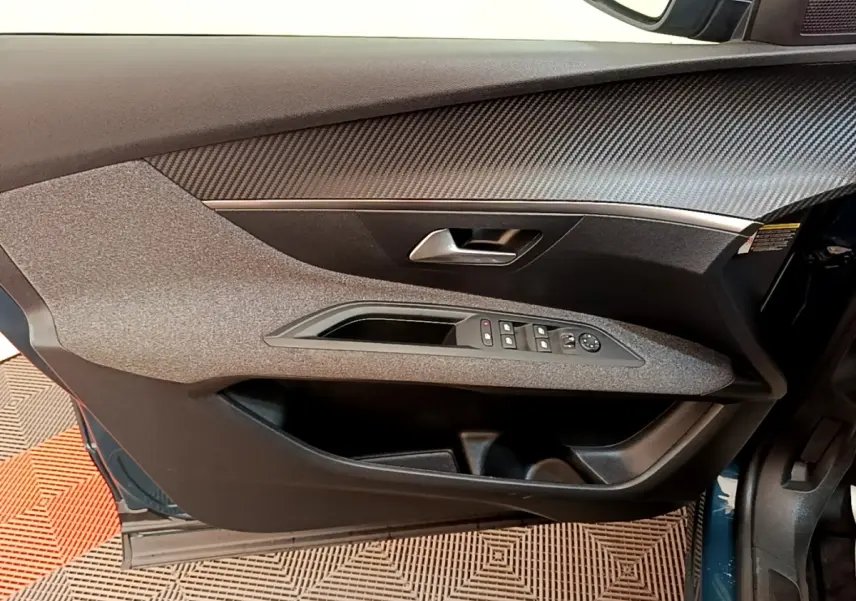 Vue intérieure côté gauche de la porte avant d’un Peugeot 3008 bleu, avec commandes des vitres et poignée argentée.