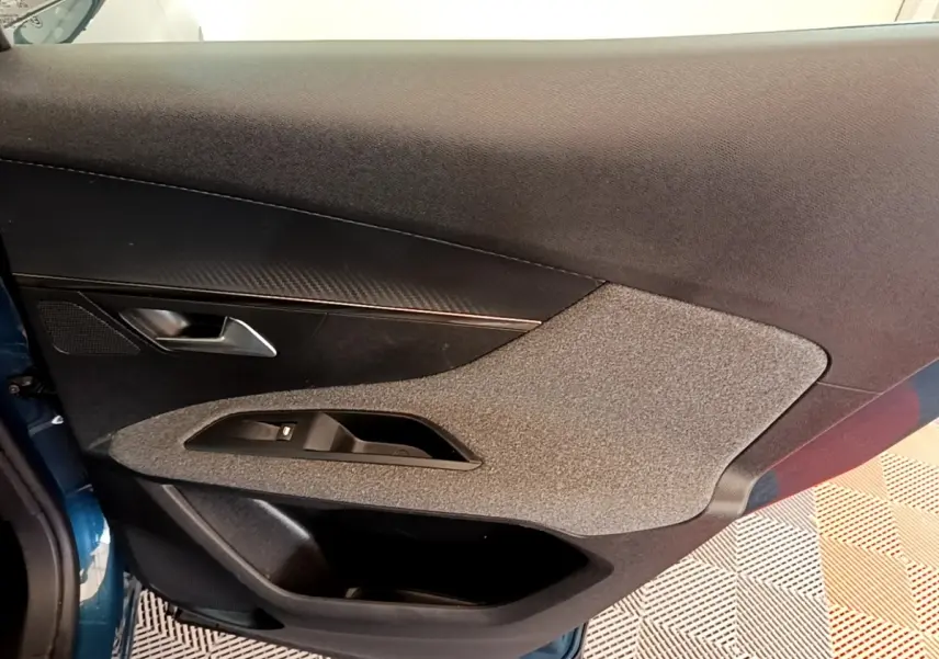 Vue intérieure côté gauche de la porte avant d’un Peugeot 3008 bleu avec garniture tissu et plastique noir.