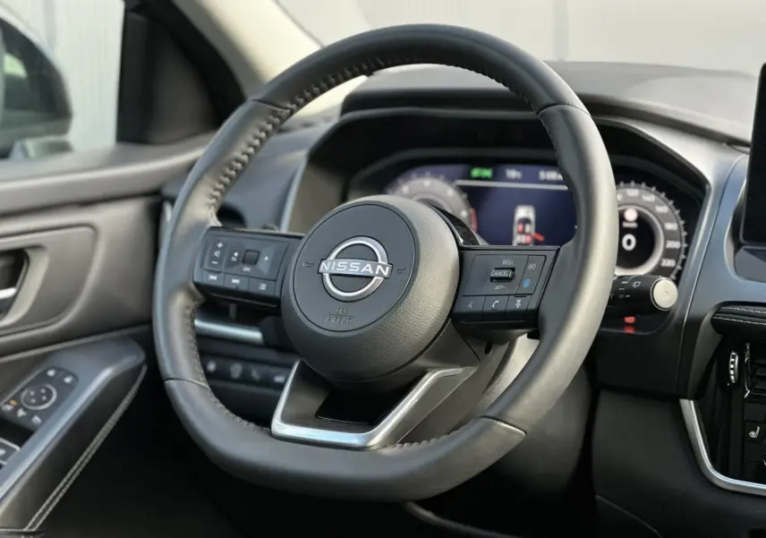 Volant cuir noir Nissan Qashqai 2025 vu de face avec commandes intégrées et tableau de bord numérique flou.