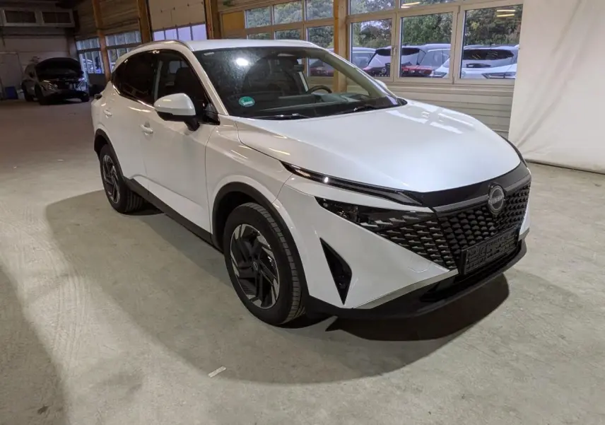 Nissan Qashqai blanc nacré vu en 3/4 avant droit, avec calandre noire et jantes alliage 18 pouces.