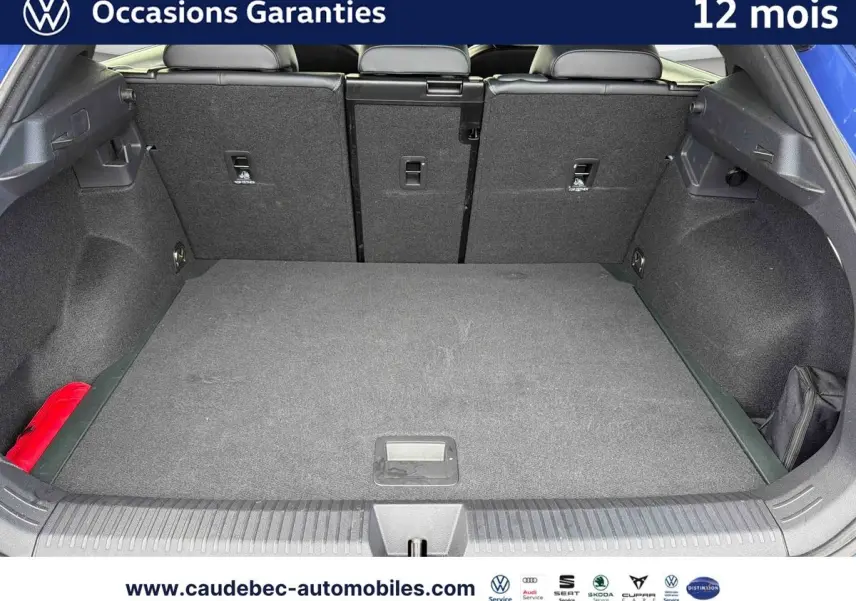 Coffre ouvert du Volkswagen T-Roc bleu, vue arrière montrant l’espace de chargement et la banquette rabattable.