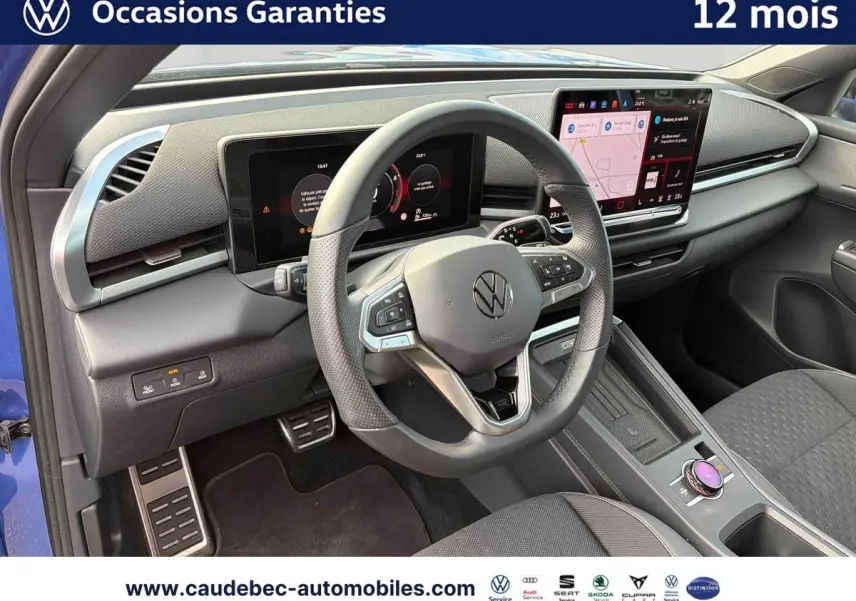 Vue intérieure côté conducteur du Volkswagen T-Roc bleu 2026, volant multifonction et écran tactile visibles.