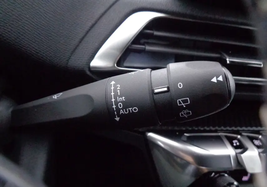 Gros plan sur la manette d'essuie-glace du Peugeot 3008 gris Artense, avec commandes et aérateurs en arrière-plan.