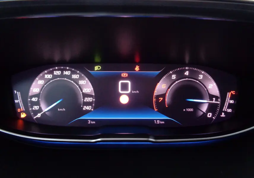 Tableau de bord numérique du Peugeot 3008 gris, affichant vitesse à 0 km/h et compte-tours au ralenti.