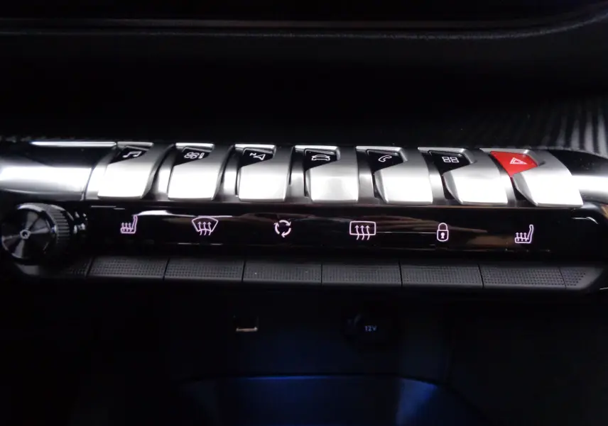 Gros plan sur la rangée de boutons argentés et les commandes tactiles éclairées du tableau de bord du Peugeot 3008 gris 2023.