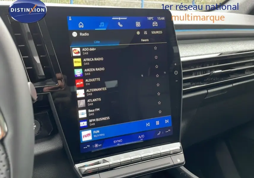 Vue rapprochée de l'écran tactile central du tableau de bord du Renault Espace noir étoile métal 2025, affichant les stations radio.