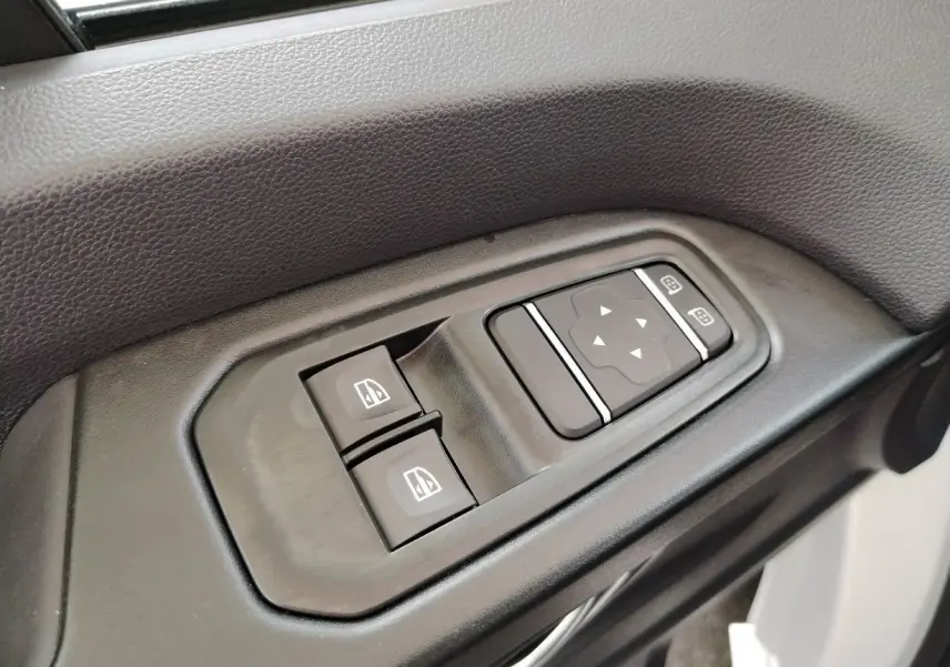 Commandes des vitres électriques et réglage des rétroviseurs sur la portière intérieure d'un Nissan Primastar blanc.