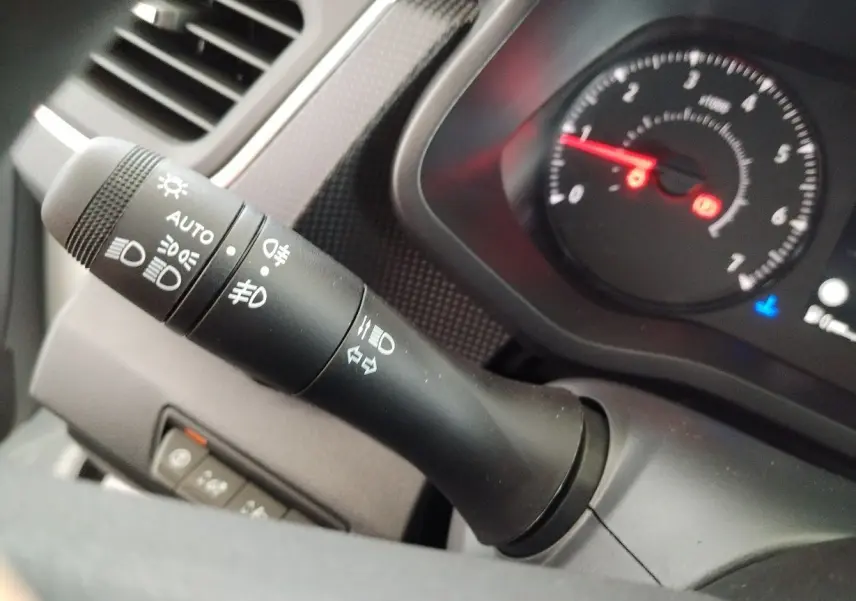 Gros plan sur la manette des phares et clignotants du tableau de bord du Nissan Primastar blanc 2025.