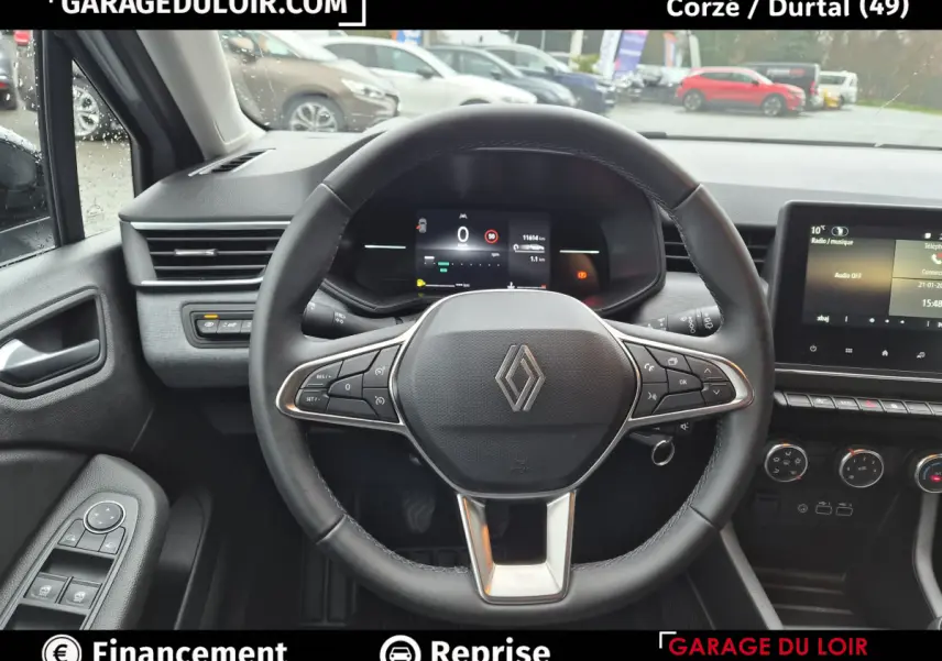 Vue intérieure centrée sur le volant cuir multifonctions de la Renault Clio gris clair avec tableau de bord numérique.