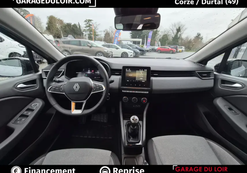 Vue intérieure avant de la Renault Clio gris clair 2025, volant multifonctions cuir et écran tactile central visible.