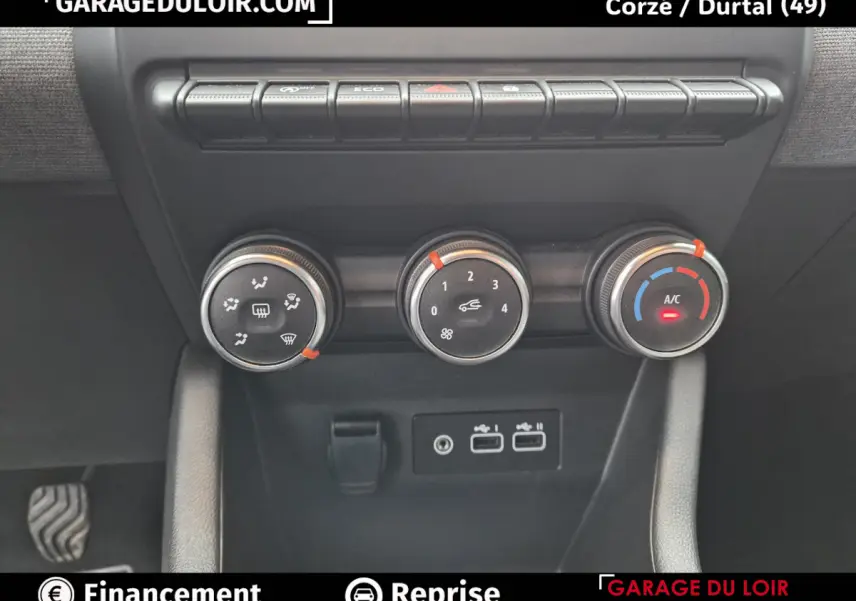 Gros plan sur les commandes de climatisation et les ports USB d'une Renault Clio gris clair, intérieur moderne et fonctionnel.