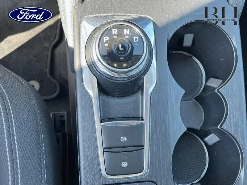 Gros plan sur la console centrale gris foncé du Ford Kuga 2022, avec sélecteur rotatif de boîte auto et porte-gobelets.